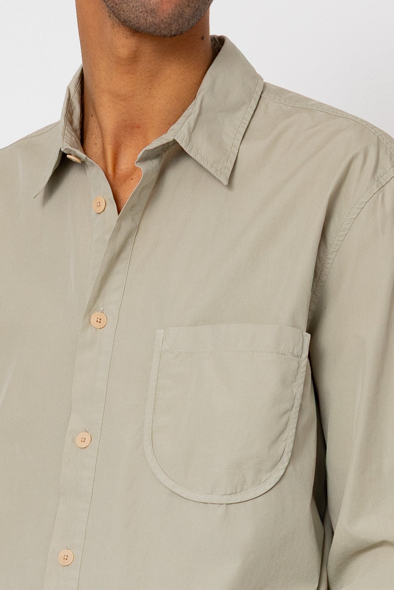 Close-up of a beige shirt with a pocket on a plain background