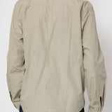 Person wearing a beige long-sleeve shirt on a white background