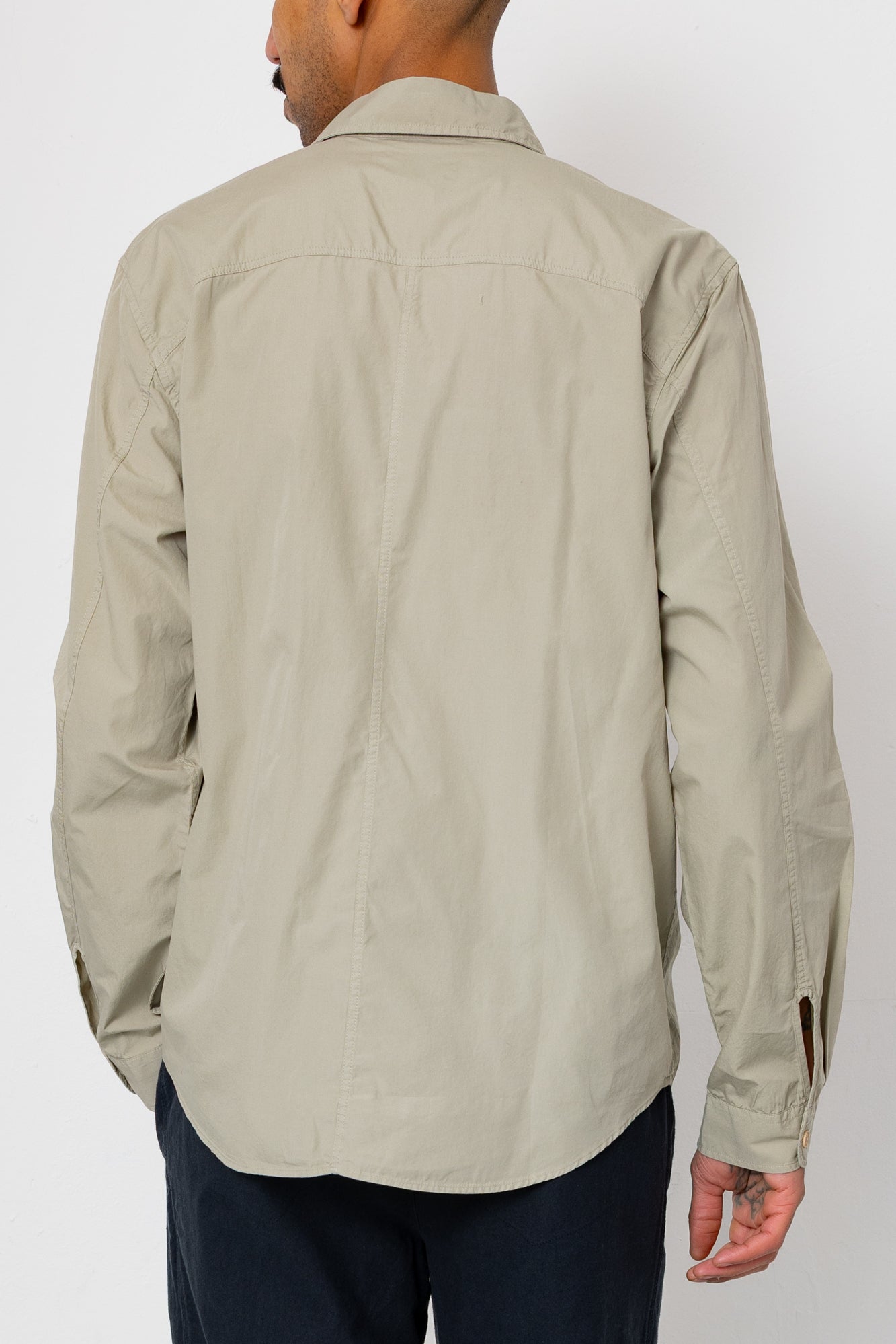 Person wearing a beige long-sleeve shirt on a white background