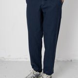 Person wearing navy pants and a blue shirt against a white background