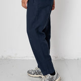 Person wearing navy pants and gray sneakers on a white background