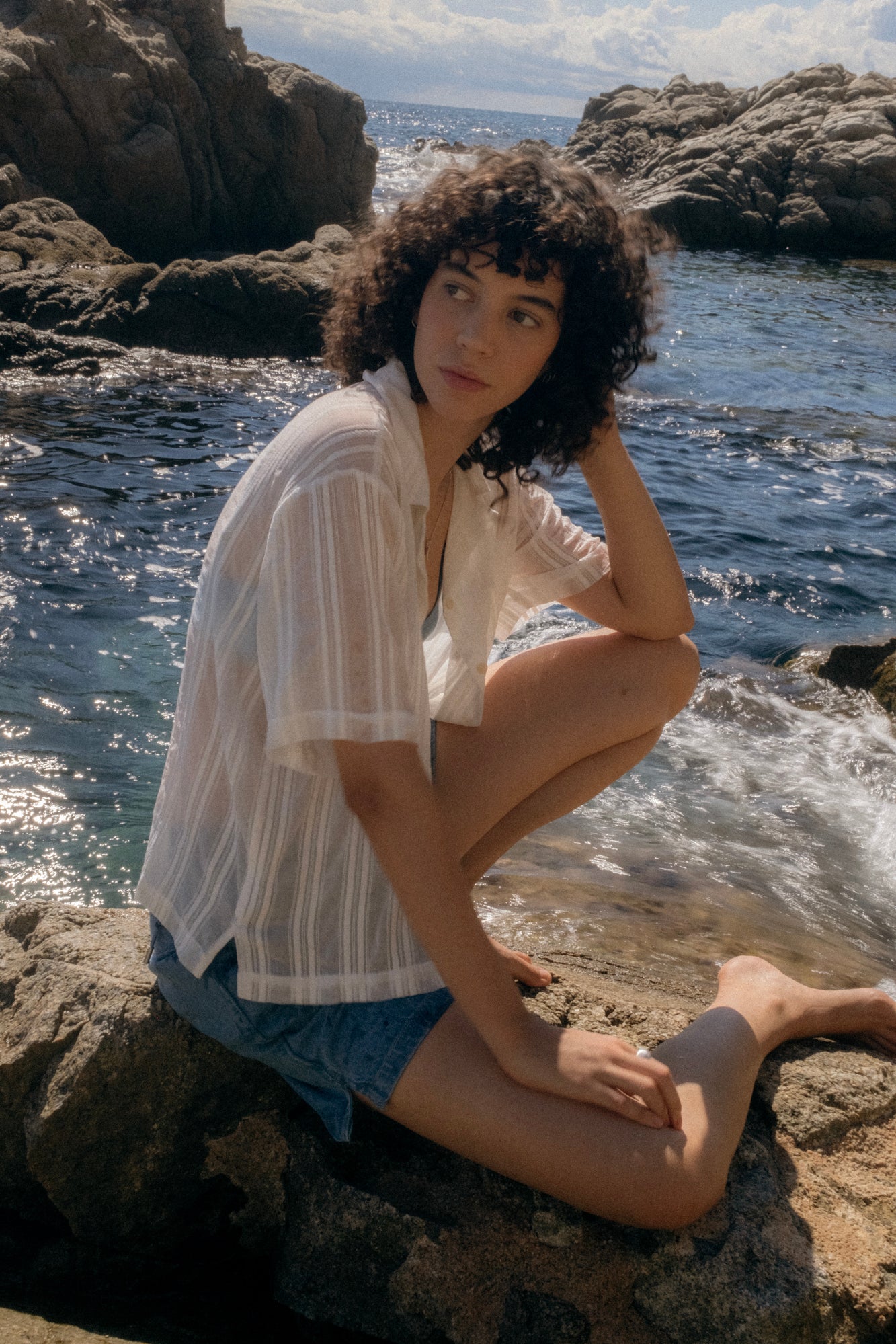 Woman sitting on rocks by the ocean with a scenic background