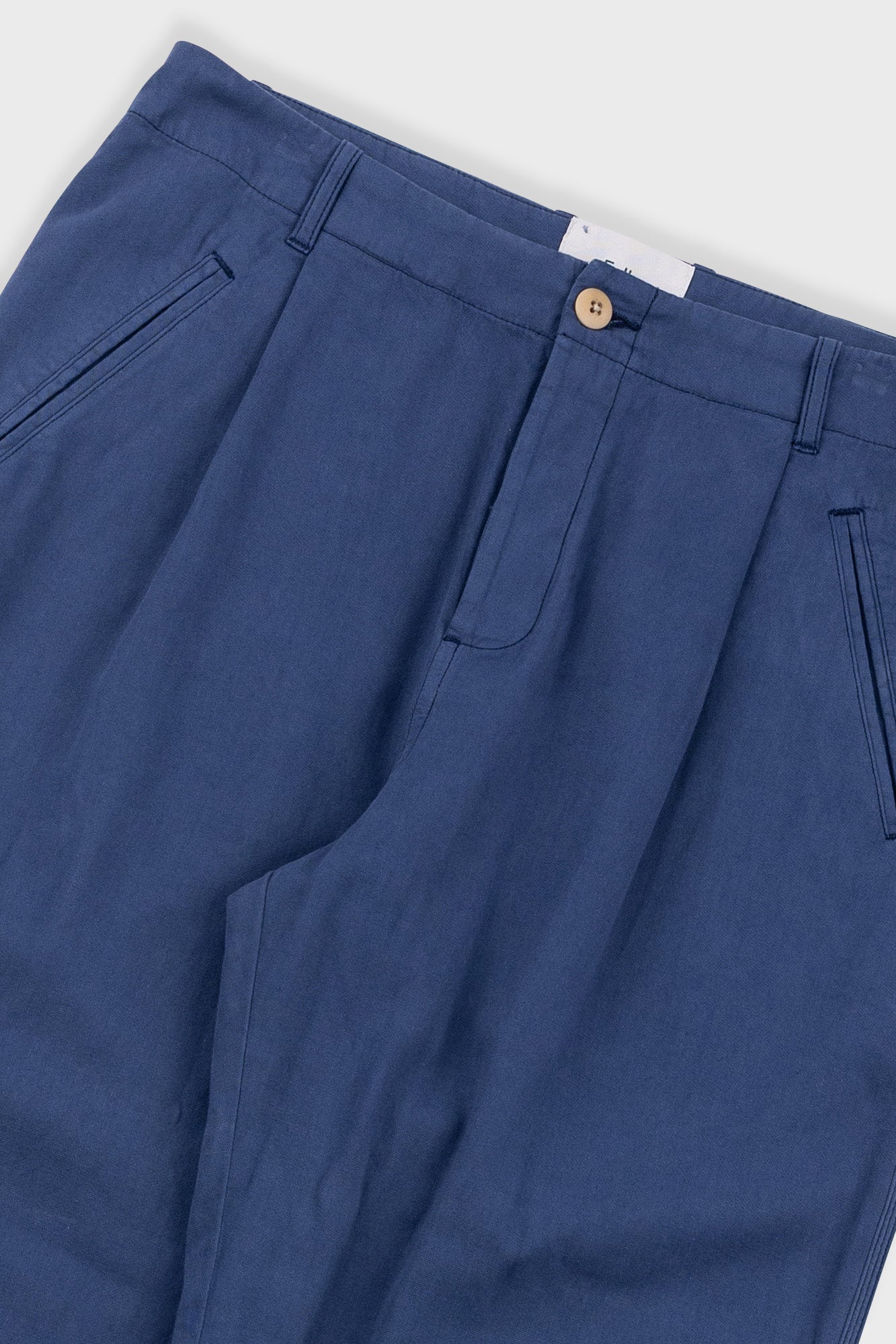Close-up of blue pants with a button on a white background