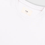 Close-up of a white t-shirt with 'Folk' brand label on a light gray background