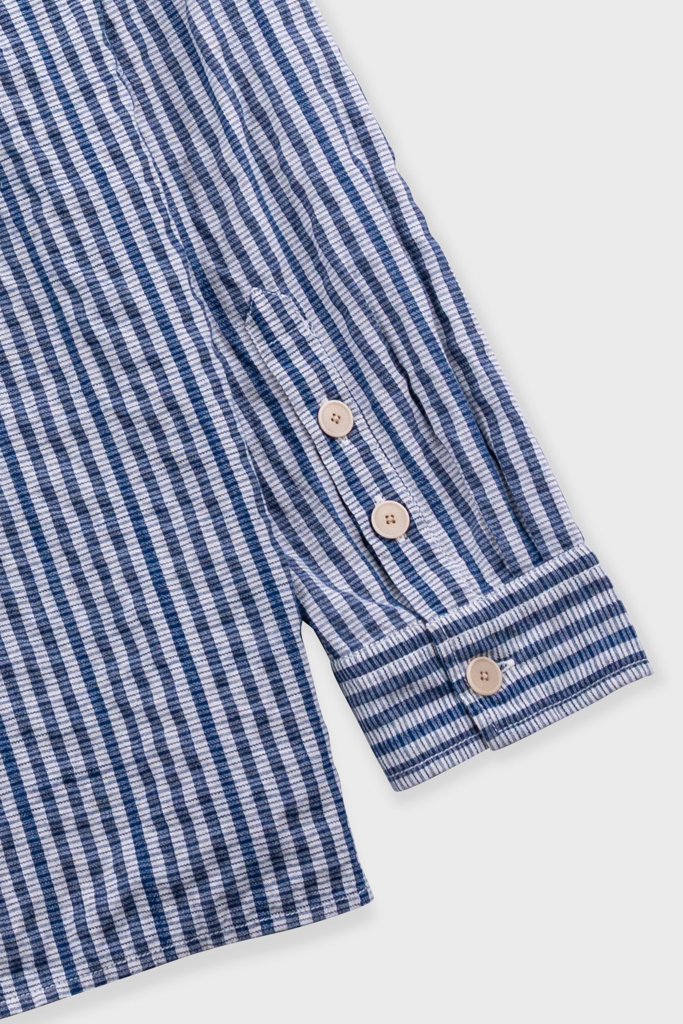 Close-up of a blue and white striped shirt with buttons on a white background