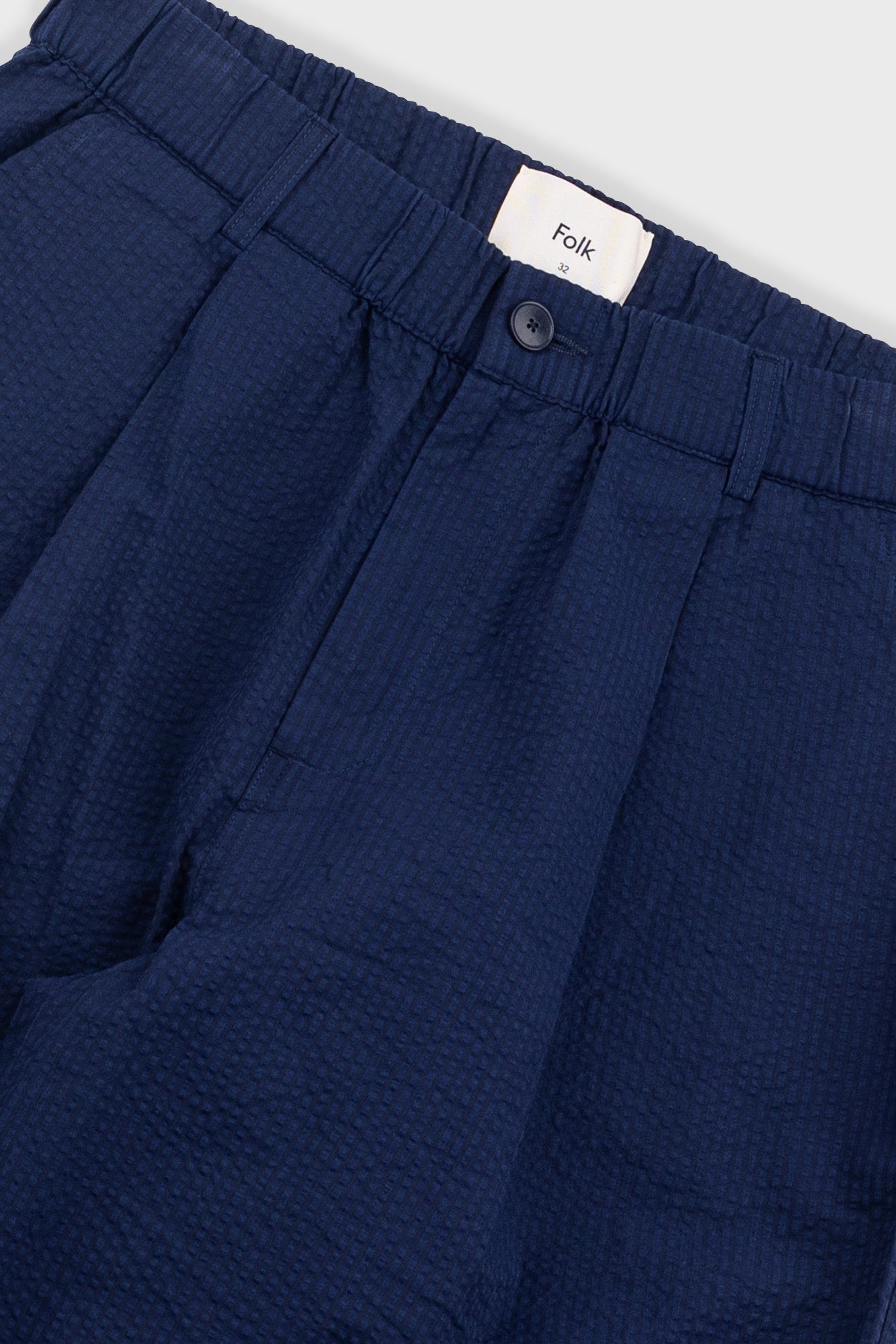 Navy blue pants with a visible brand label on a light gray background