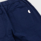 Close-up of navy blue pants with a small white logo on a light gray background