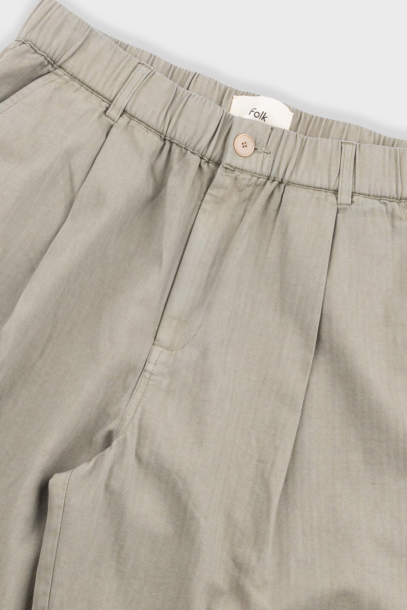 Beige pants with a visible brand label on a light gray background