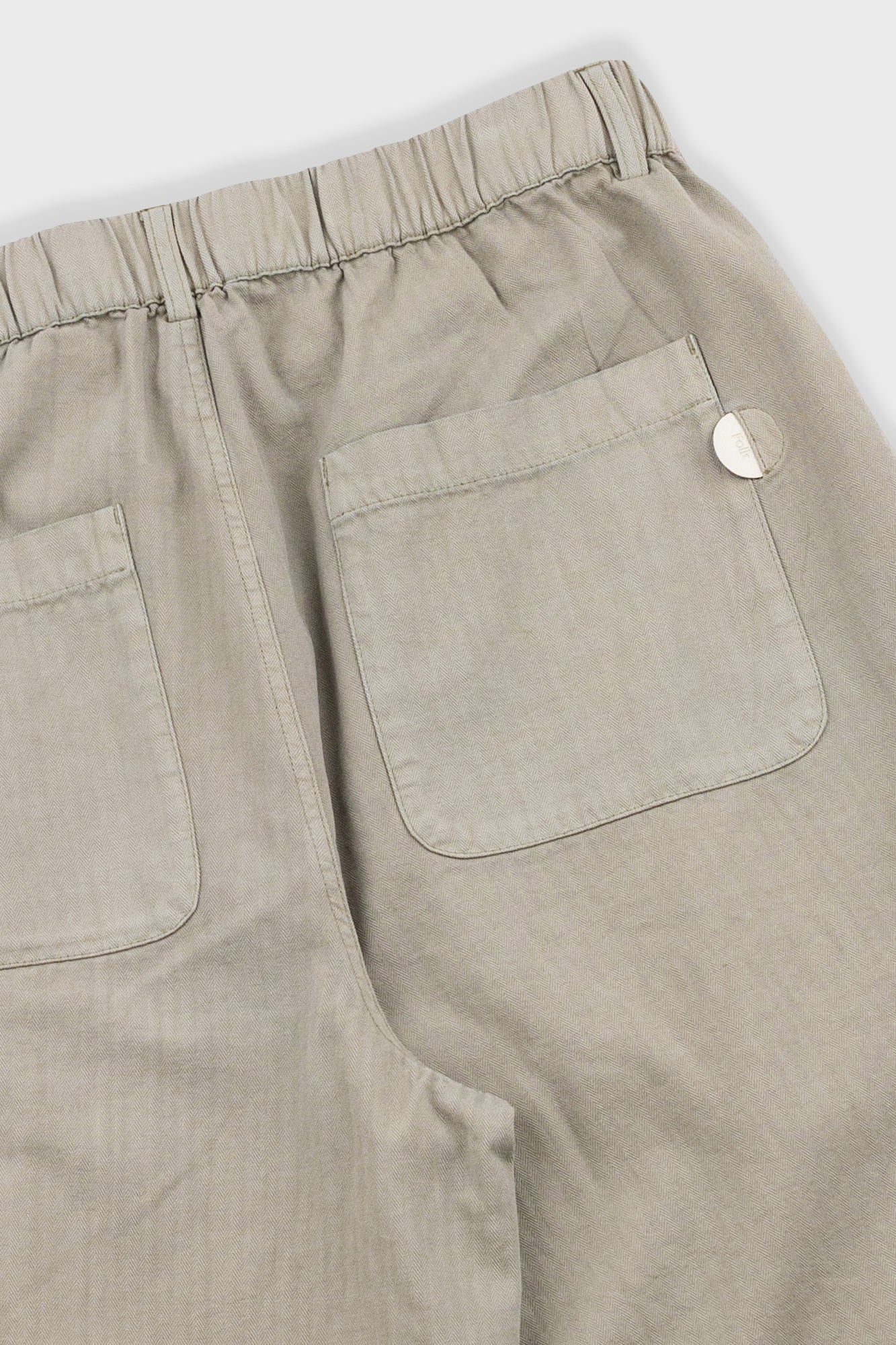 Close-up of beige pants with a pocket on a white background