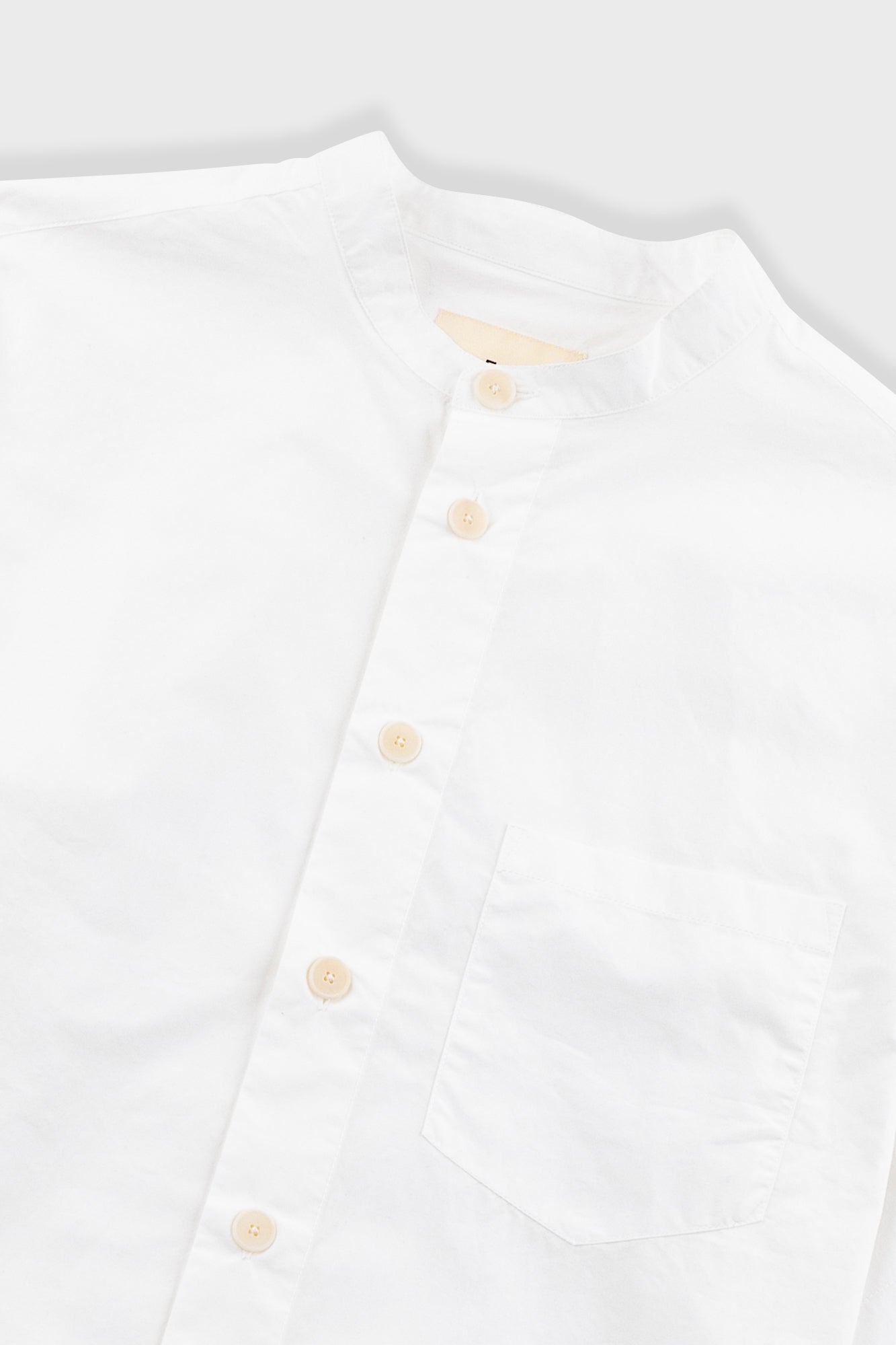 White shirt with beige buttons on a light gray background