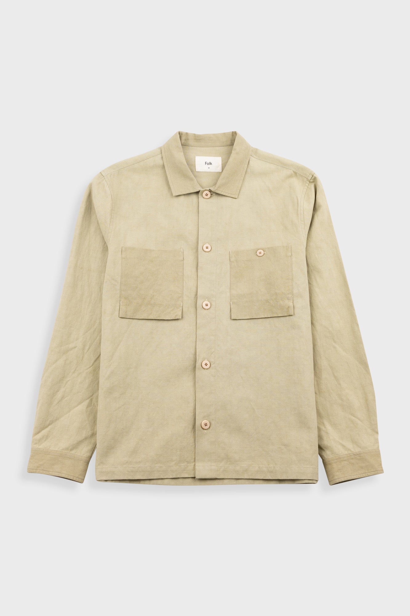 Beige shirt with two front pockets on a light gray background