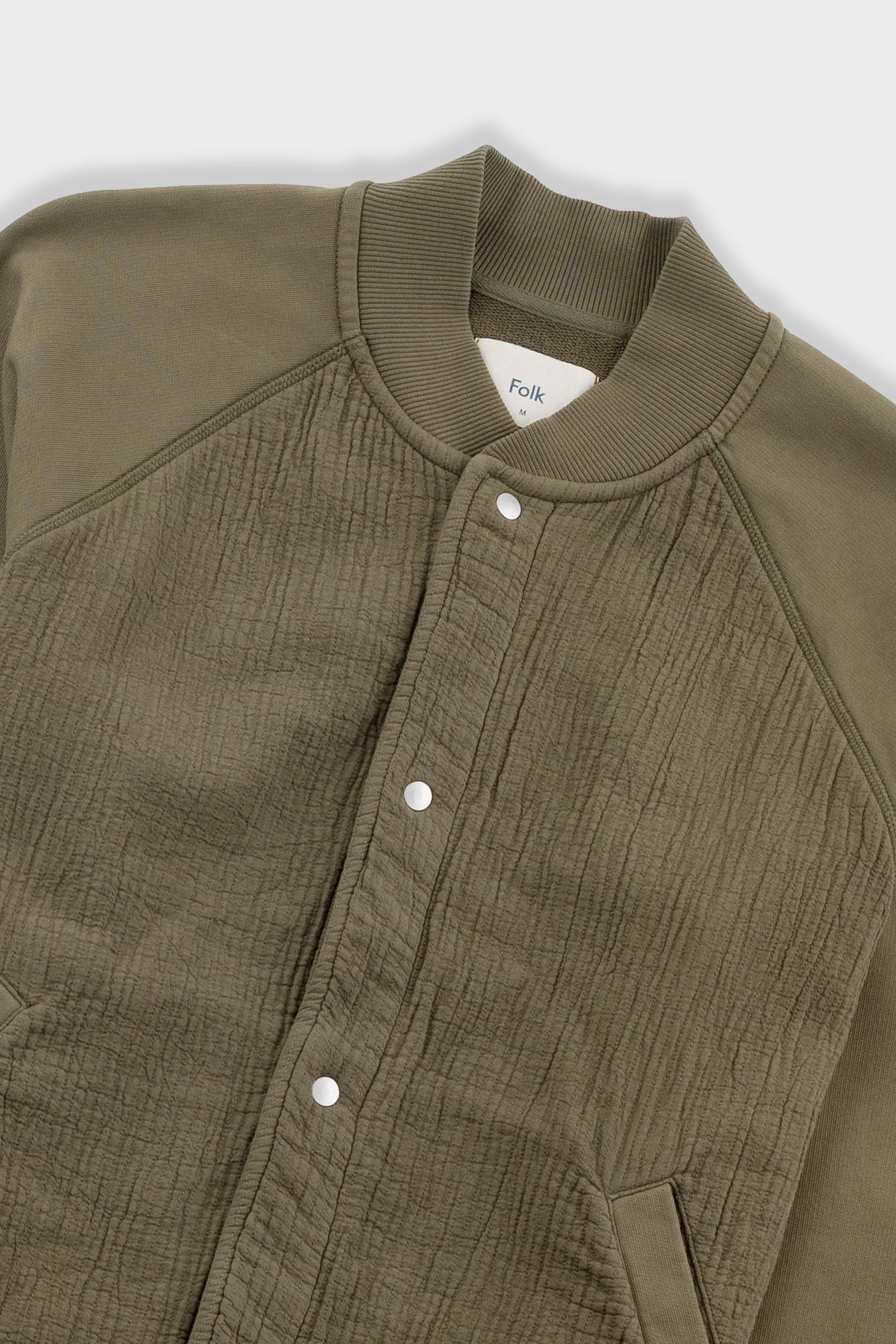 Close-up of a green jacket with a brand label on a white background