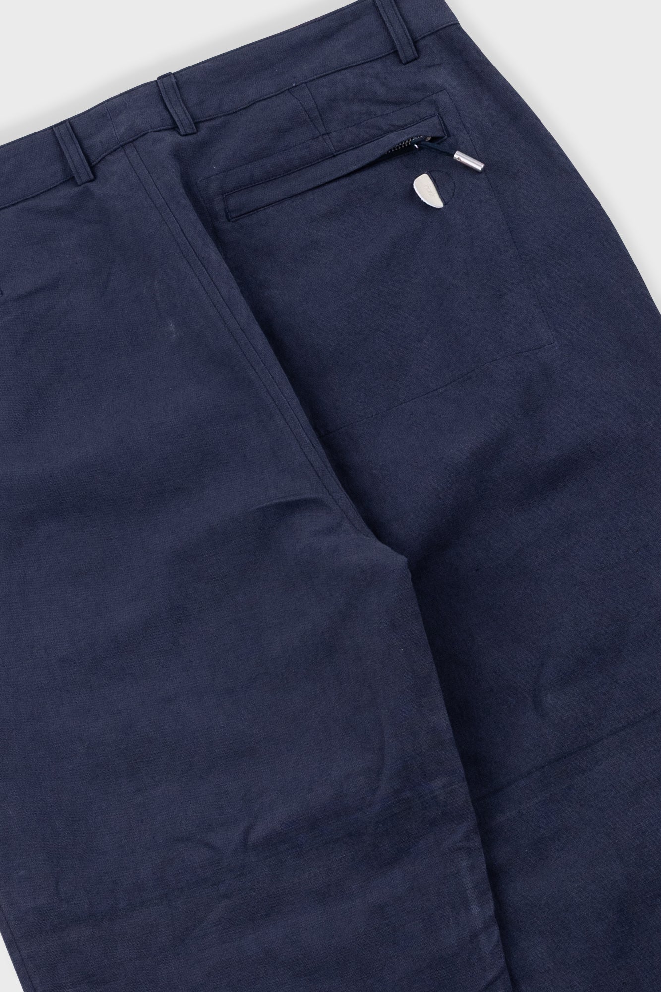 Navy blue pants with a close-up of the waistband and zipper on a white background