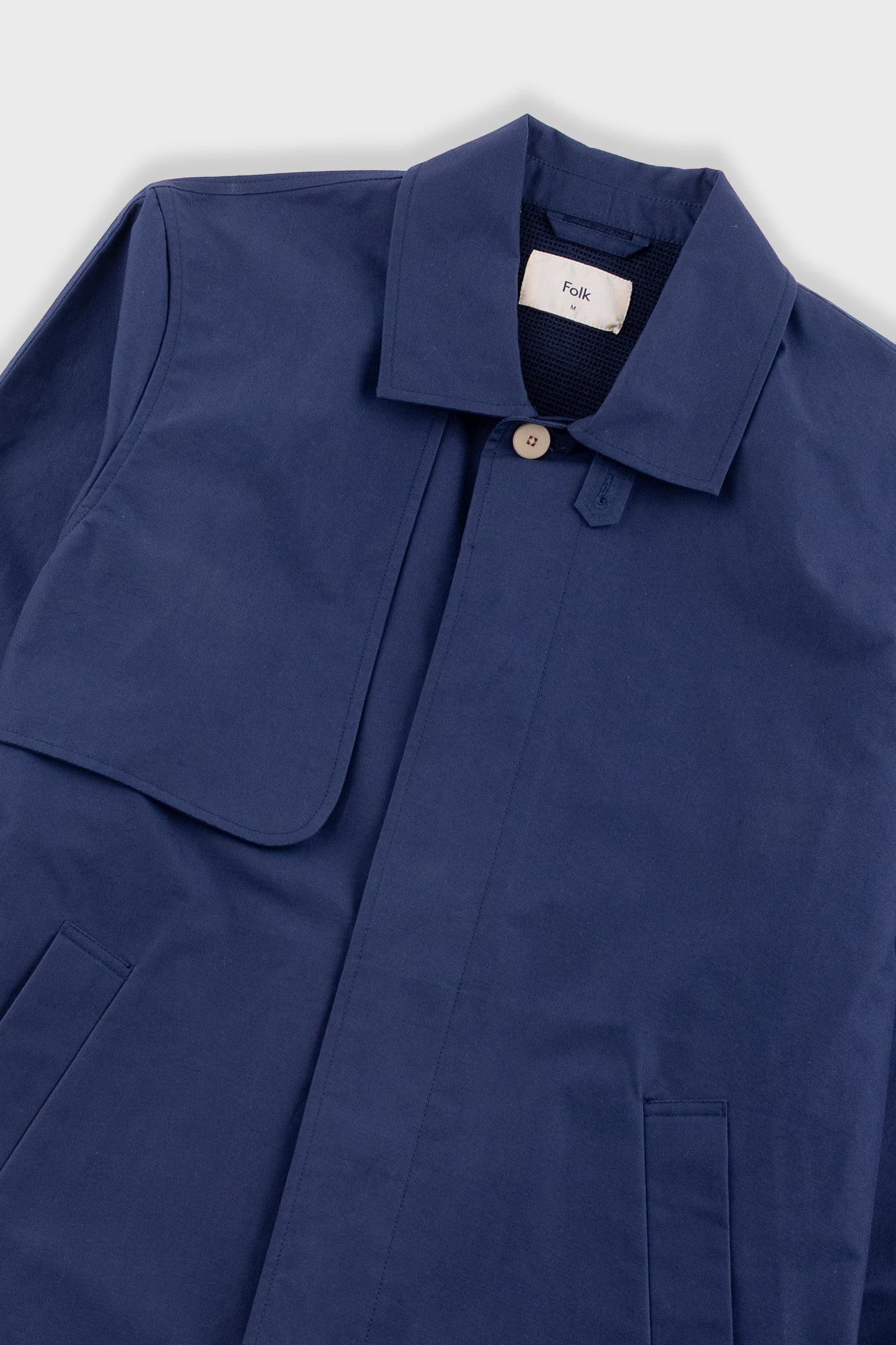 Navy blue coat with a brand label on a light gray background