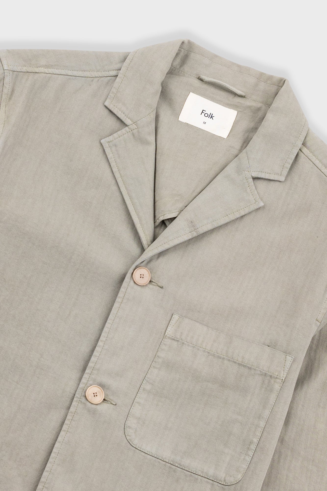 Beige blazer with brand label against light grey background