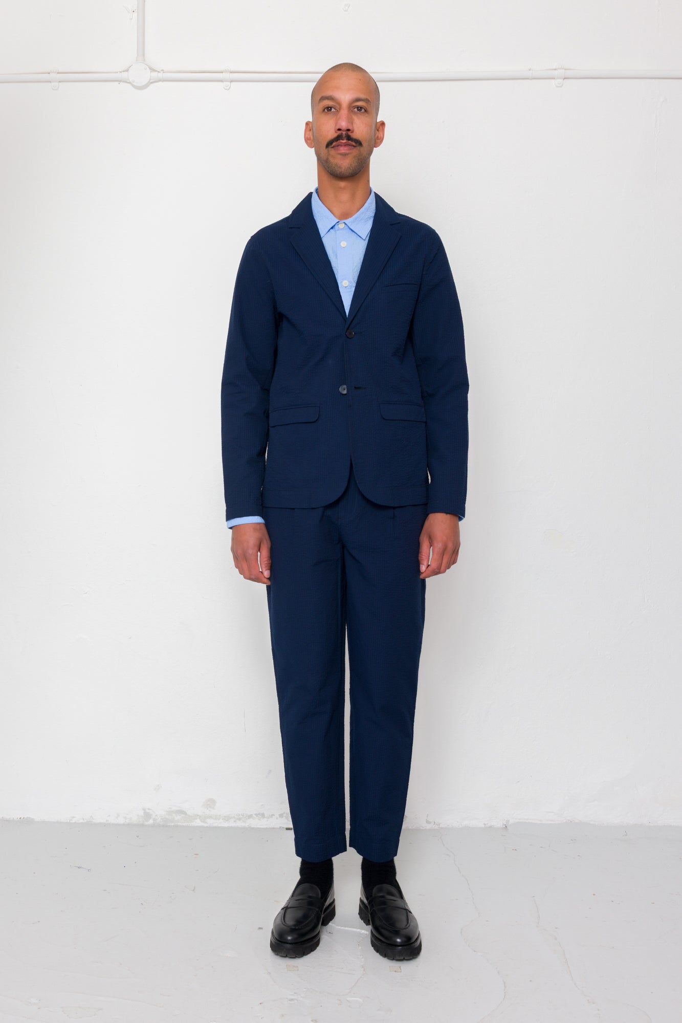 Man wearing a navy suit with a white shirt against a white background