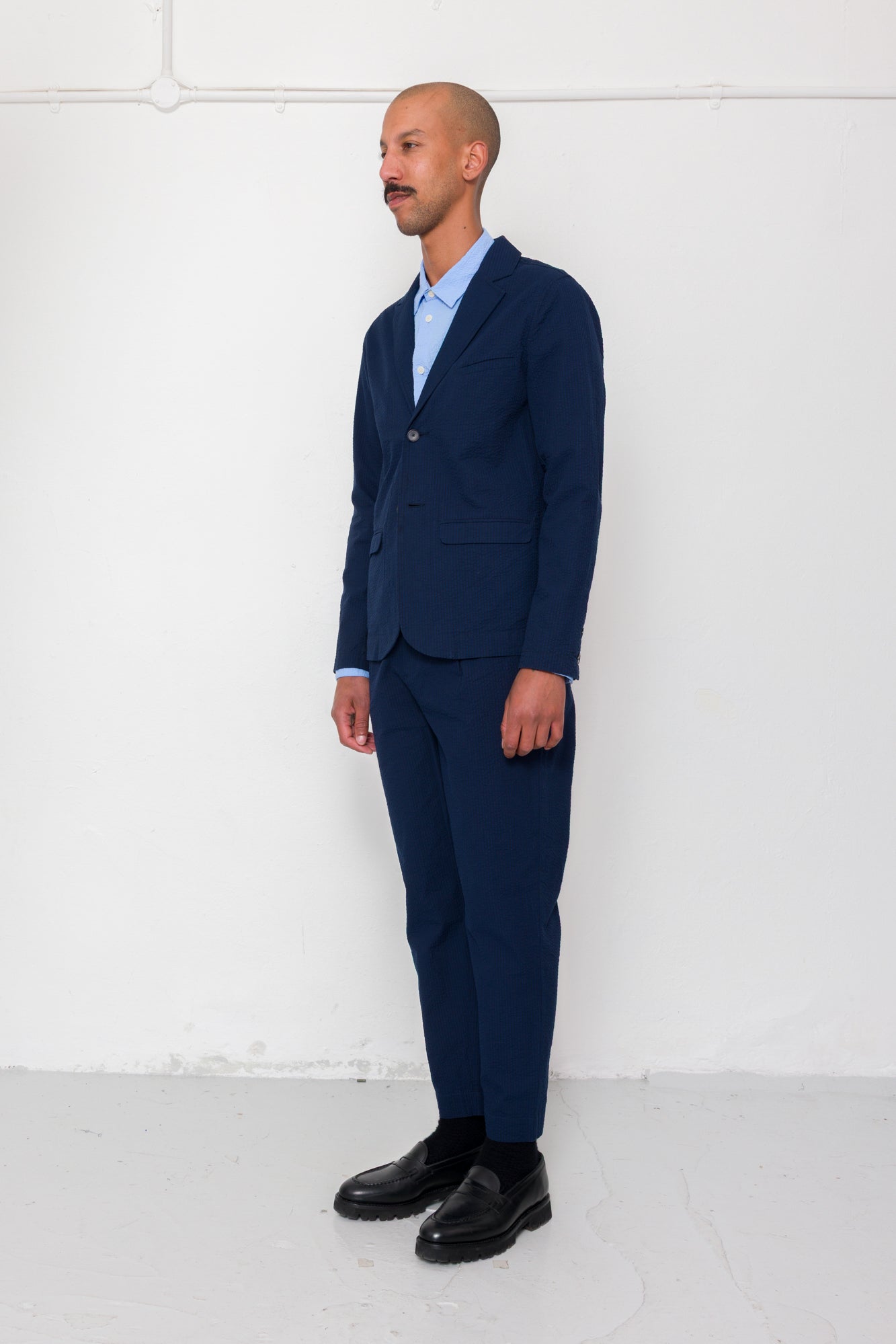 Man wearing a navy suit with a light blue shirt against a white background