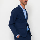 Man wearing a navy suit and light blue shirt against a white background