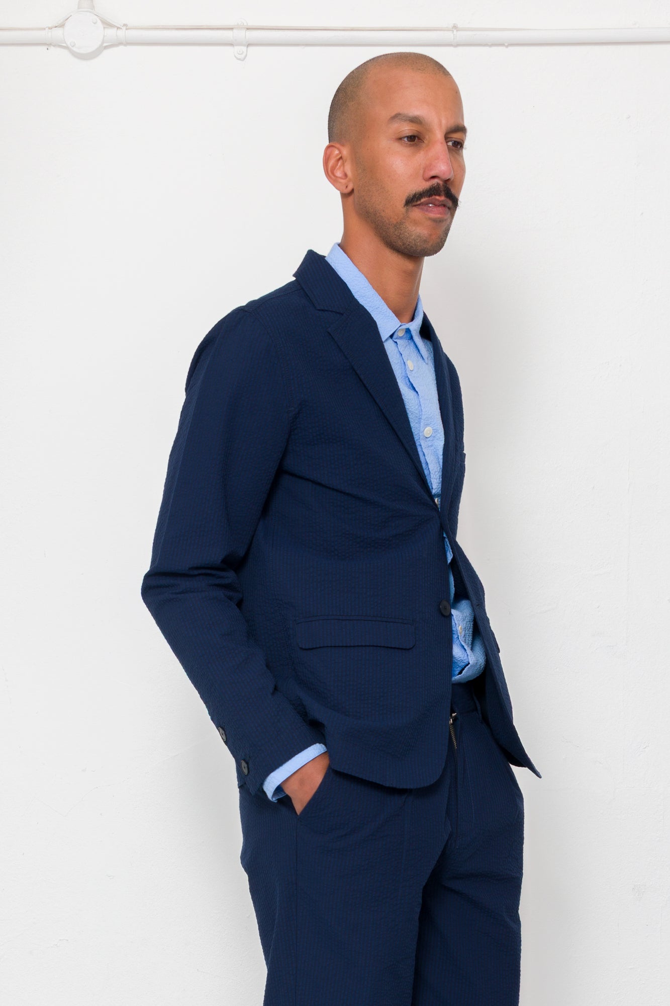 Man wearing a navy suit and light blue shirt against a white background