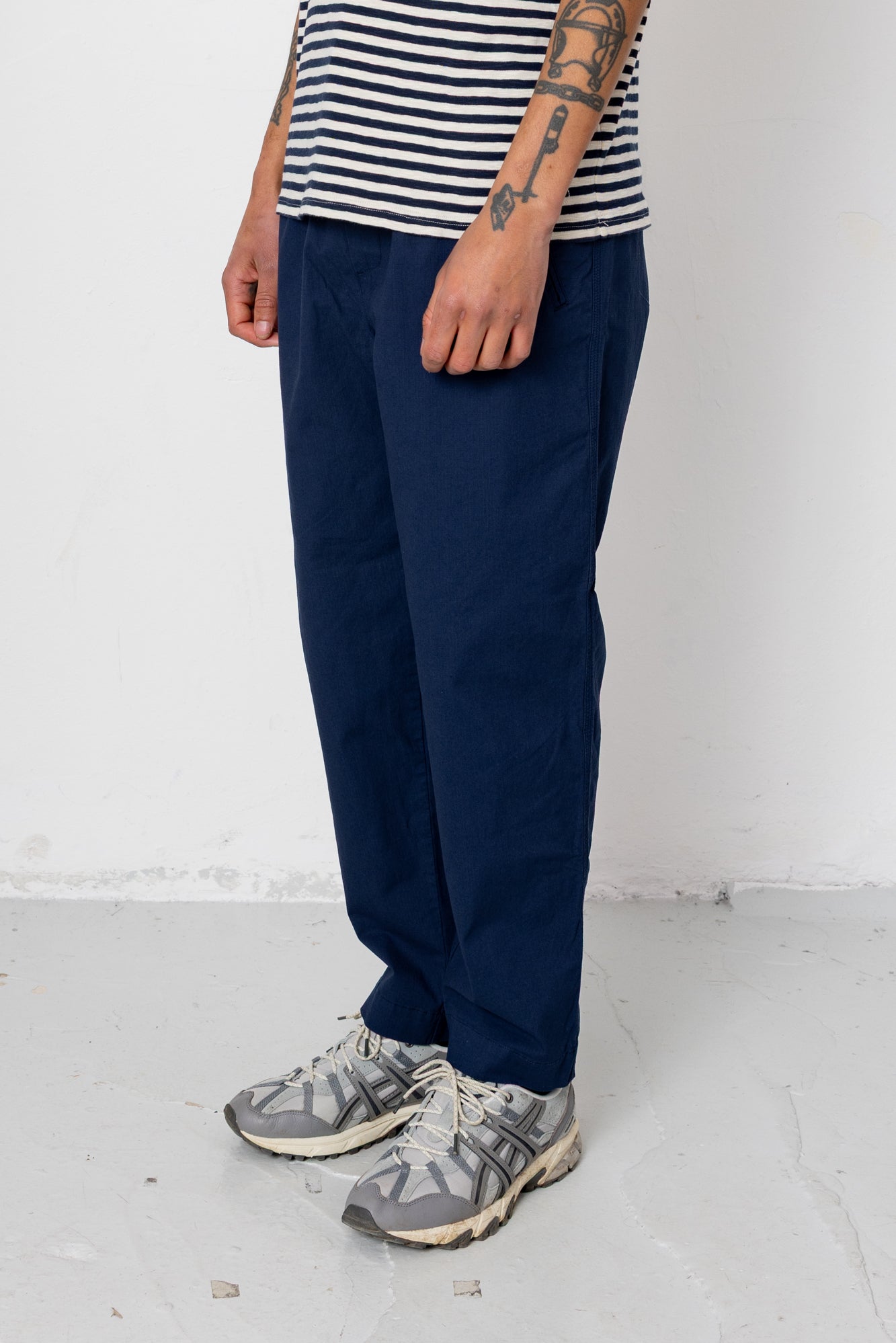 Person wearing navy pants and a striped shirt on a white background