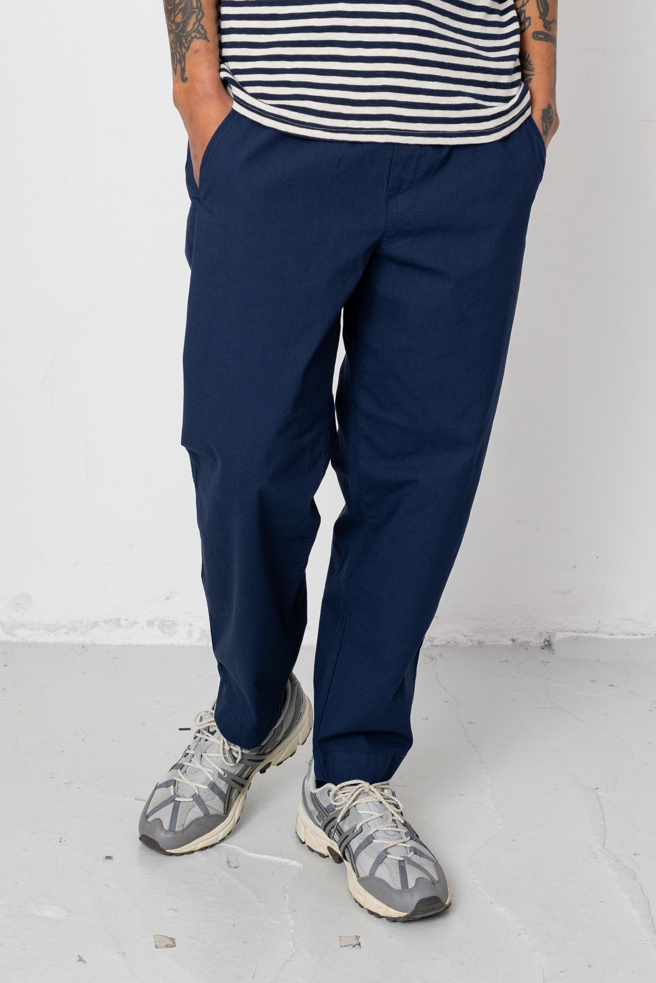Person wearing navy pants and a striped shirt on a white background
