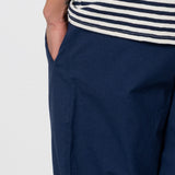 Navy pants with a white and blue striped shirt on a light gray background