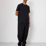 Man wearing a black outfit standing against a white background