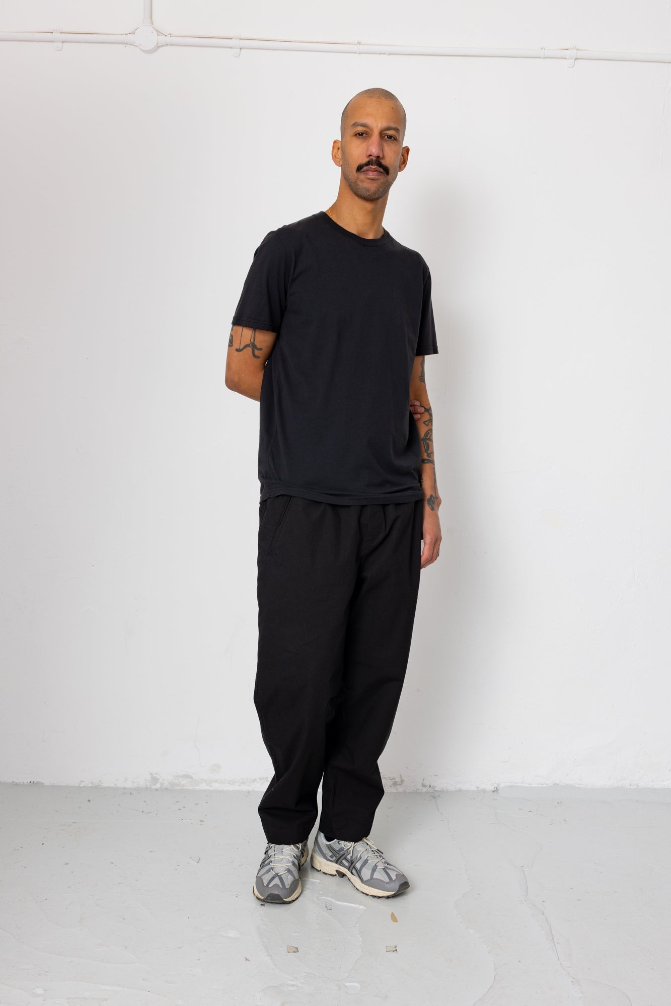 Man wearing a black outfit standing against a white background
