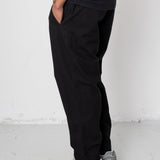 Person wearing black pants and gray sneakers on a white background