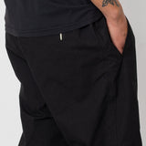 Person wearing black pants and a black shirt on a plain background