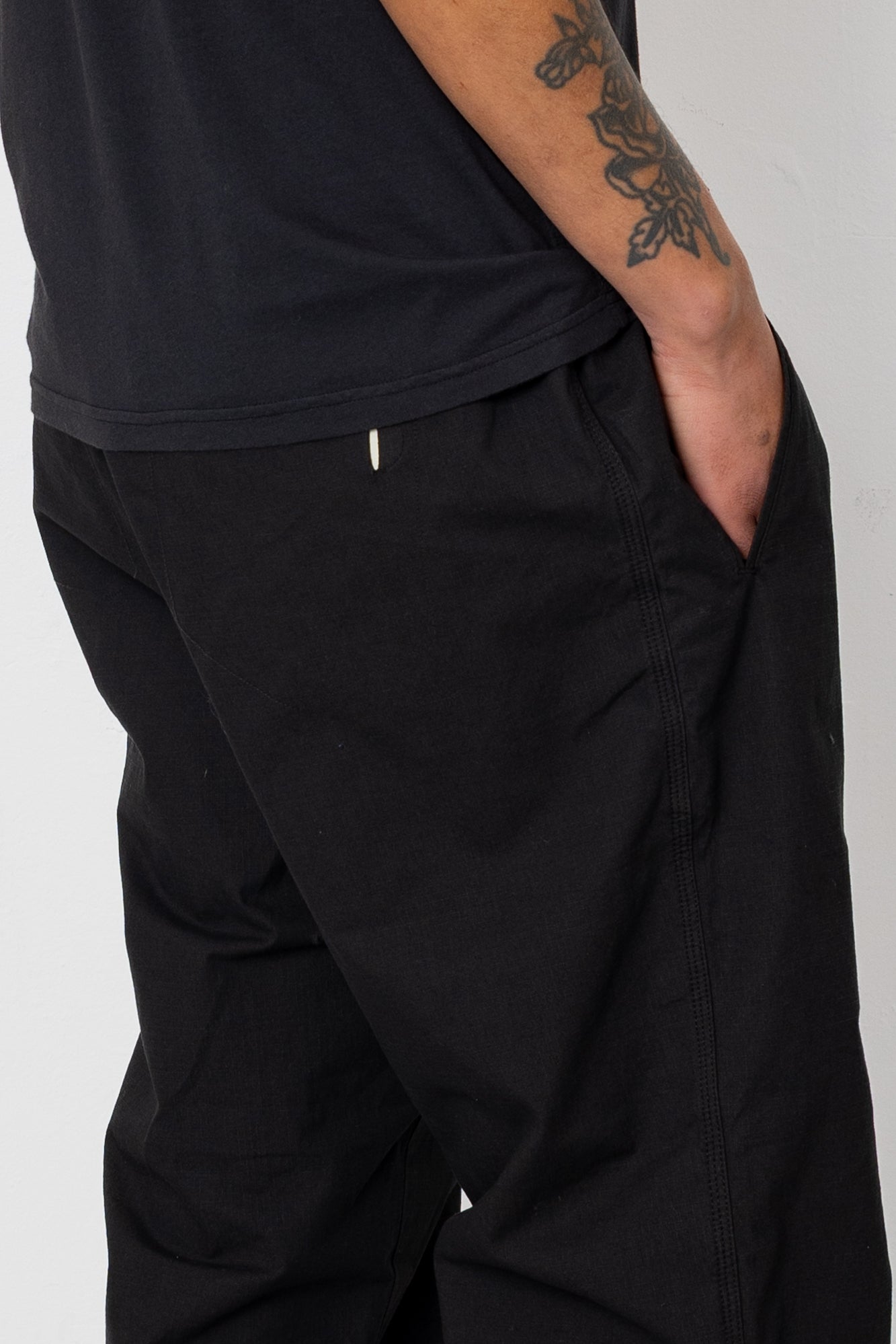Person wearing black pants and a black shirt on a plain background