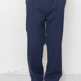 Person wearing navy pants and a white shirt against a white background