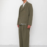 Man wearing a green suit standing against a white wall