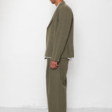 Man wearing a green suit standing against a white wall