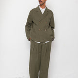 Man wearing a green suit standing against a white wall