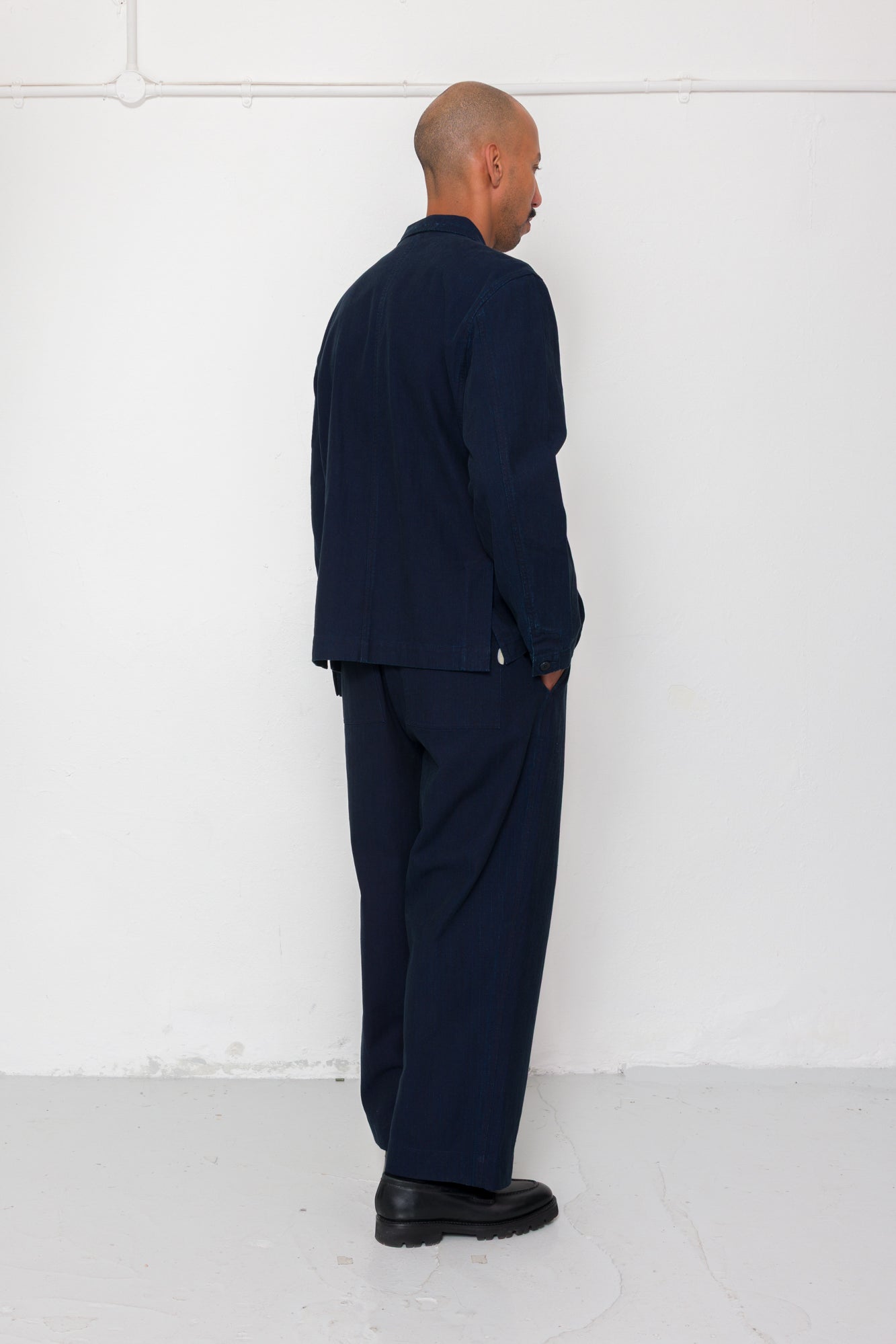 Man wearing a navy suit standing against a white wall