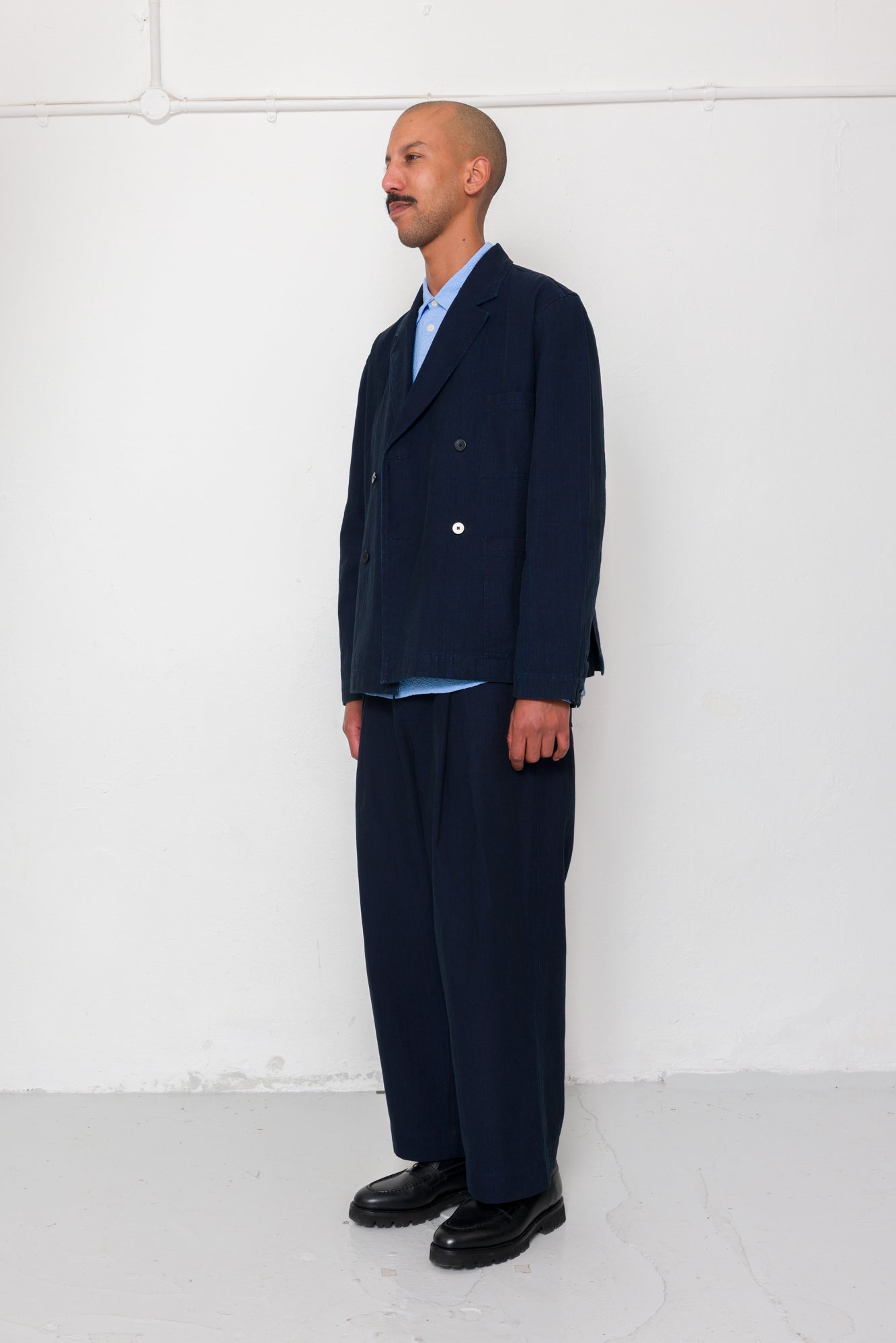 Man wearing a navy suit standing against a white background