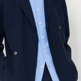 Navy blazer over a light blue shirt on a plain background