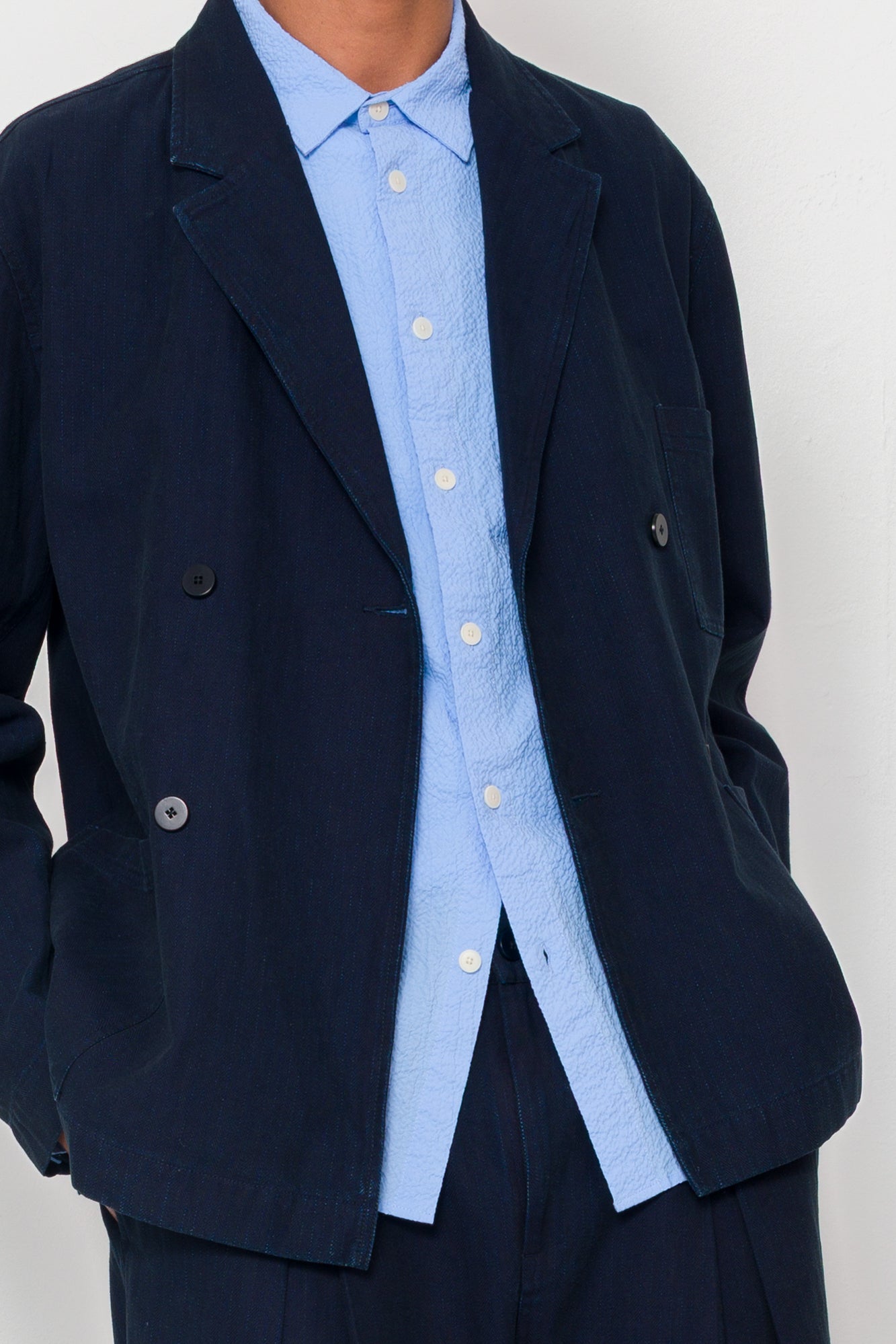 Navy blazer over a light blue shirt on a plain background