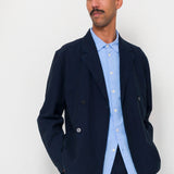 Man wearing a navy blazer and light blue shirt against a white background