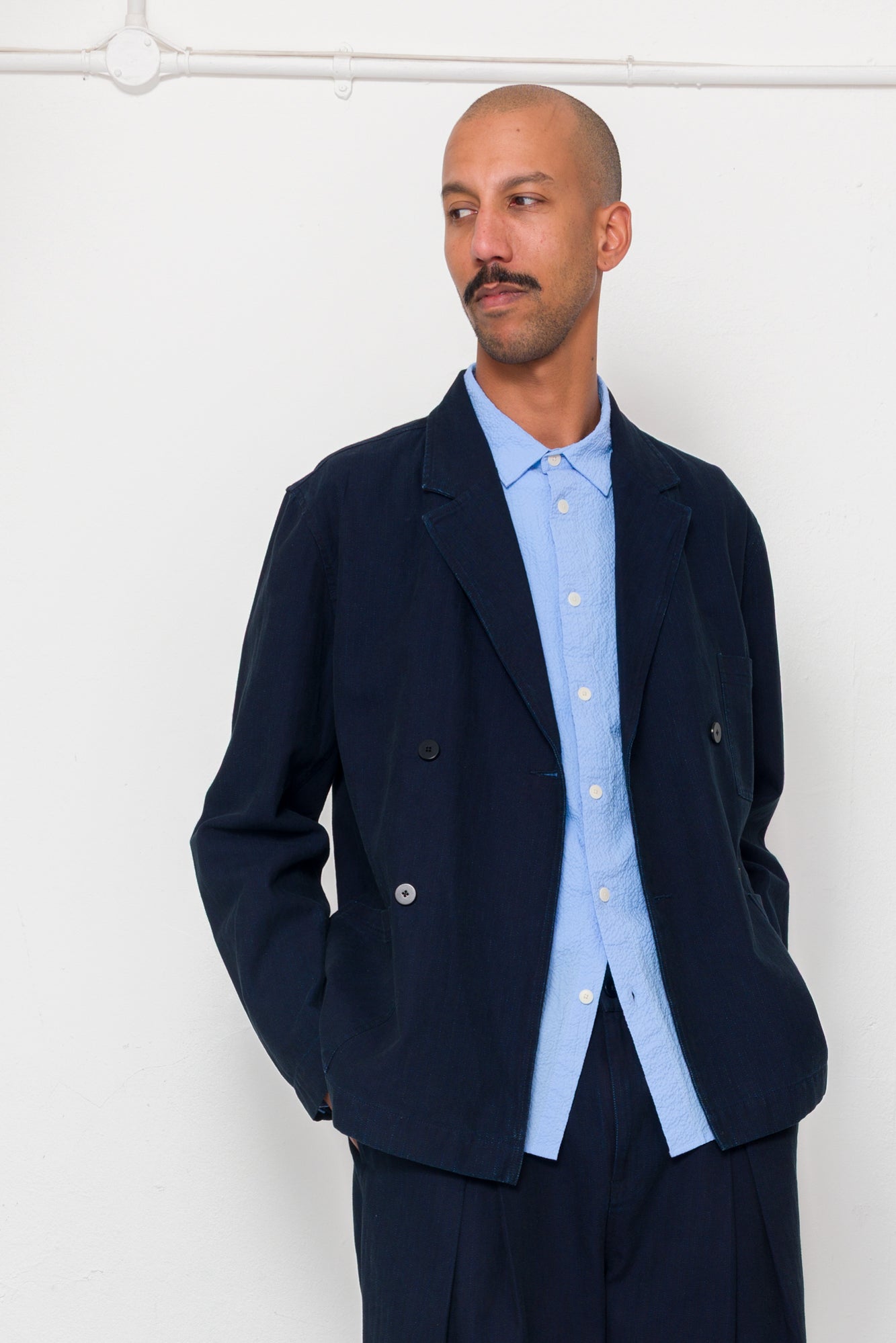 Man wearing a navy blazer and light blue shirt against a white background