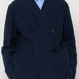 Man wearing a navy blue jacket over a light blue shirt on a white background