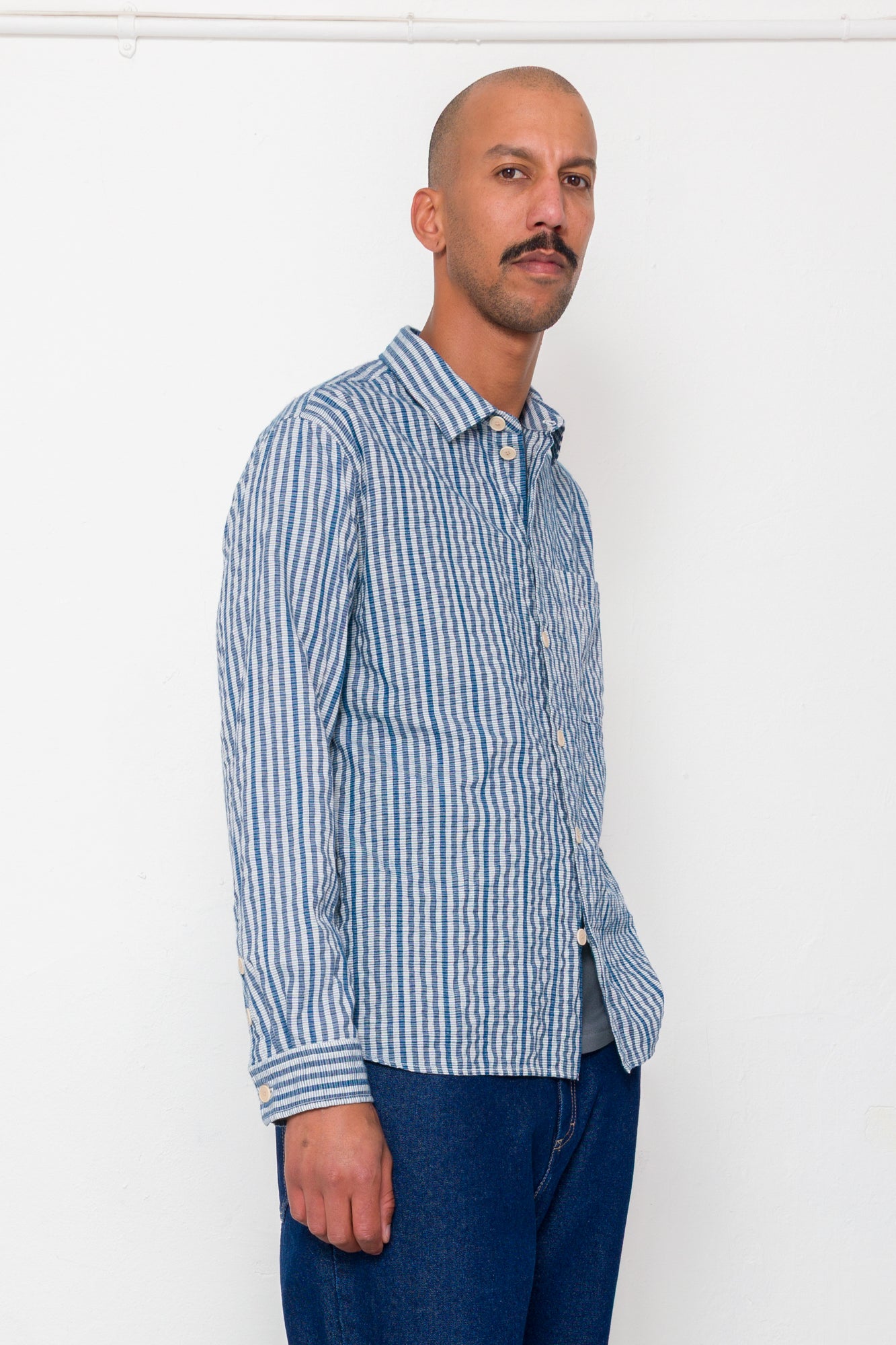 Man wearing a blue and white striped shirt against a white background
