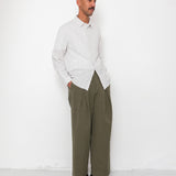 Man wearing a light gray shirt and olive green pants against a white background