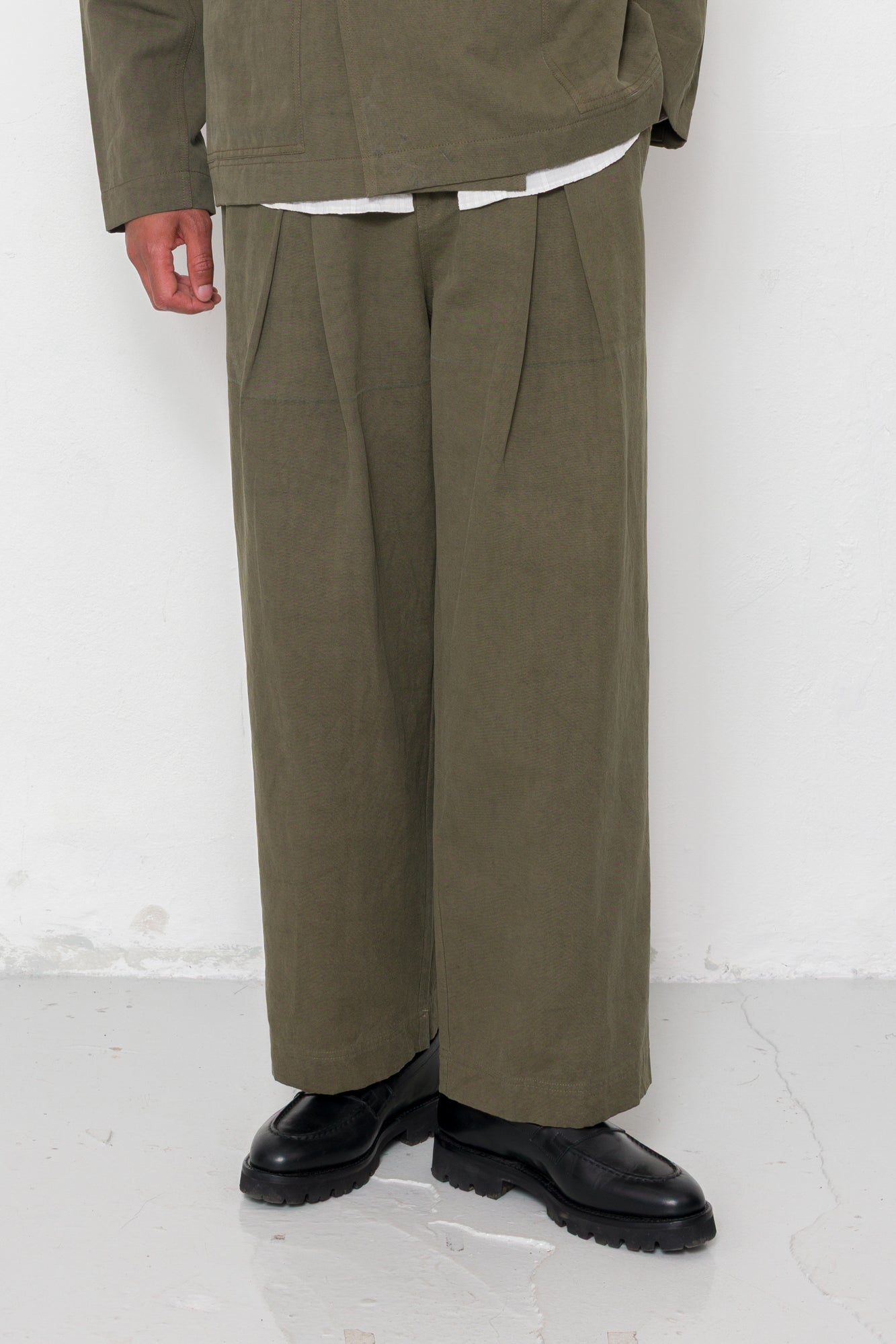 Person wearing a green suit with wide-leg pants on a white background