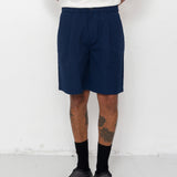 Person wearing navy shorts, white shirt, black shoes, and socks on a white background