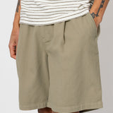Man wearing striped t-shirt and beige shorts in front of white wall