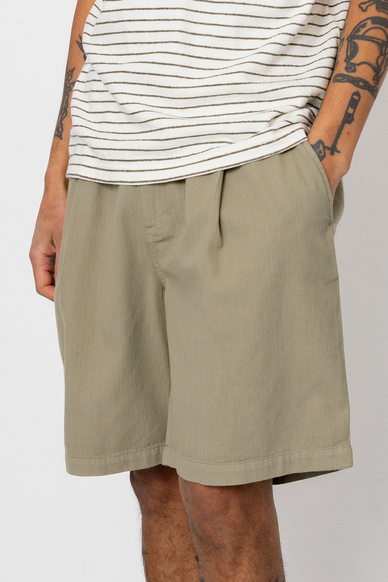 Man wearing striped t-shirt and beige shorts in front of white wall
