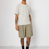 Man wearing striped t-shirt and beige shorts in front of white wall