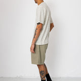 Man wearing striped t-shirt and beige shorts in front of white wall